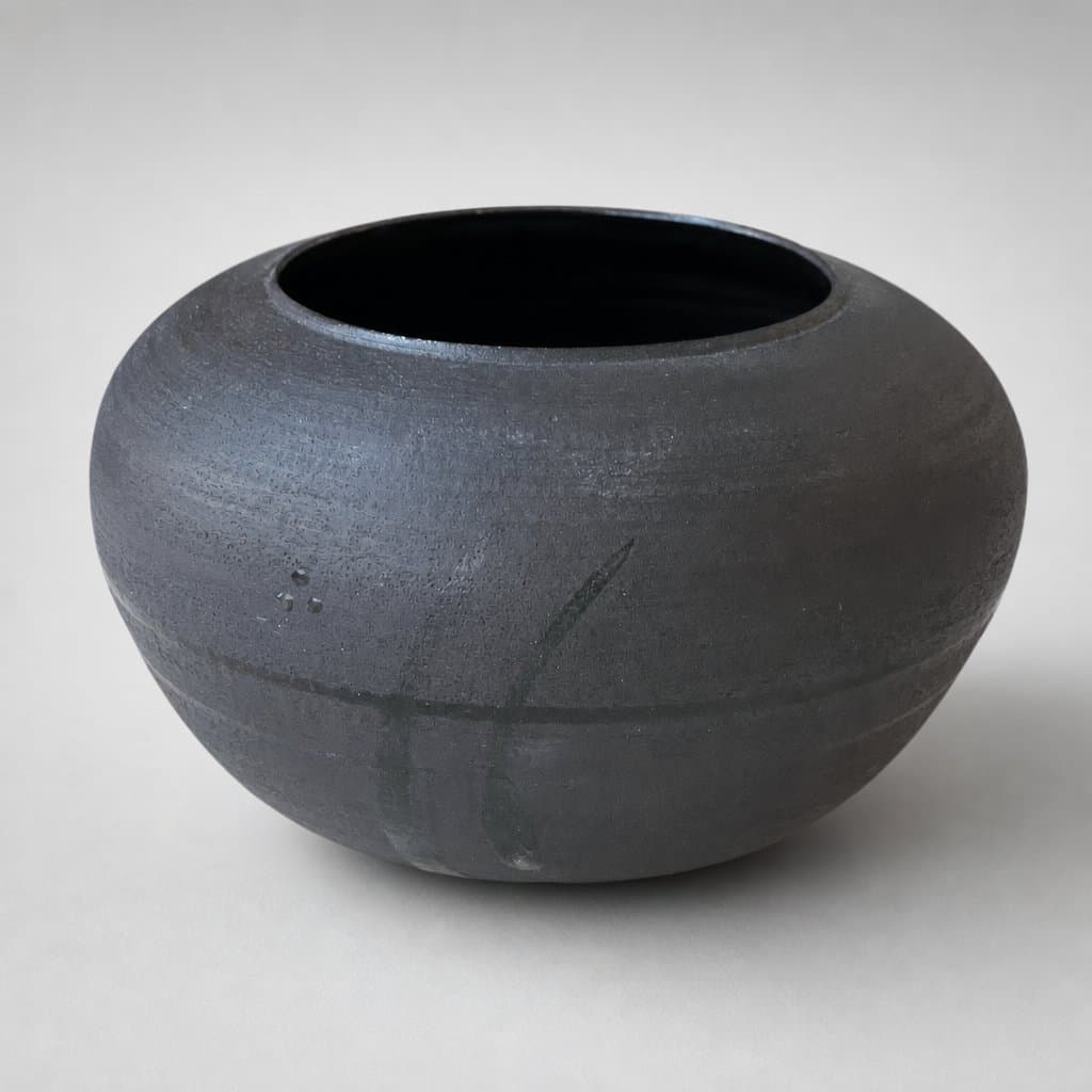 Low, wide, black stoneware vase with glossy, translucent interior and decoration