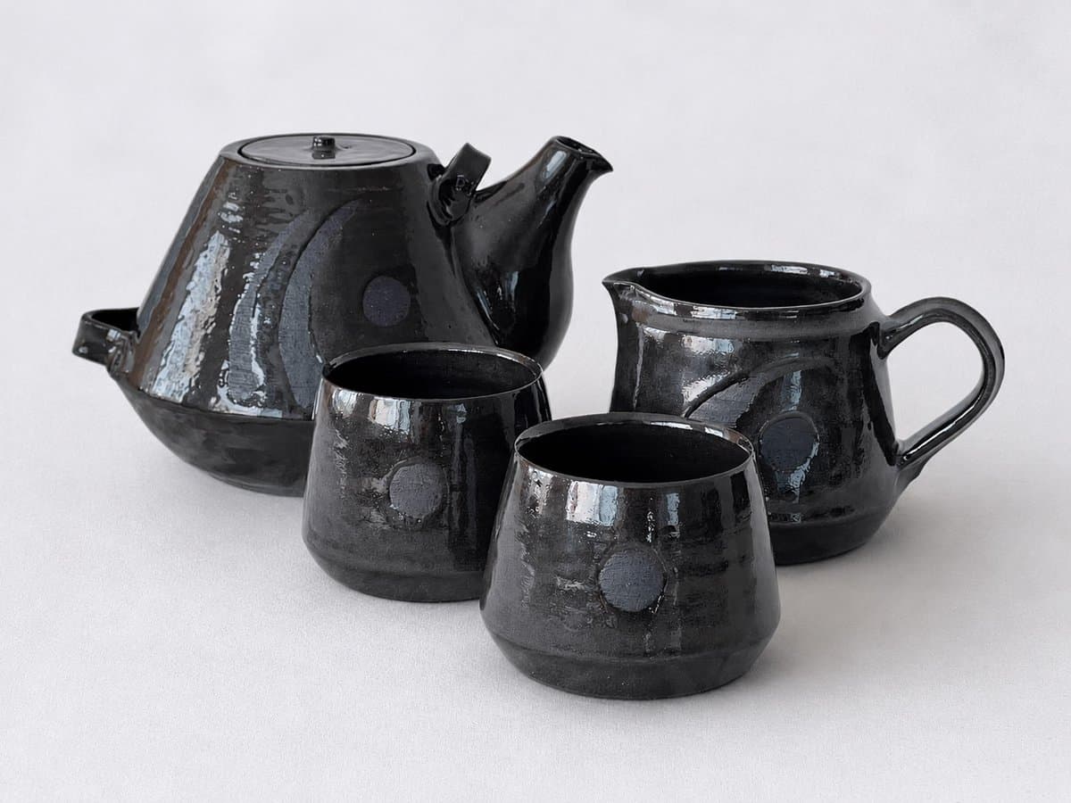 Black stoneware tea set with translucent glaze - teapot, milk pourer, two cups